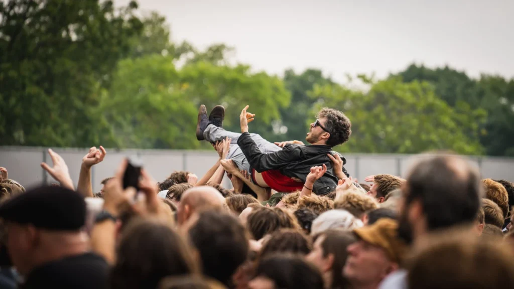 A fan crowd-surfs at an IDLES festival show, capturing IDLES live in 2026